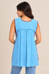 Back view of handmade baby blue gingham Mexican apron showing its pleated design and sleeveless construction.
