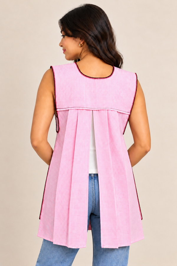 Back view of handmade baby pink gingham Mexican apron showing its pleated design and sleeveless construction.