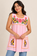 Woman modeling handmade baby pink gingham Mexican apron with butterfly and floral cross-stitch embroidery.