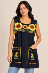 Young woman modeling a black handmade Mexican apron with colorful sunflower cross-stitch embroidery and front pockets.