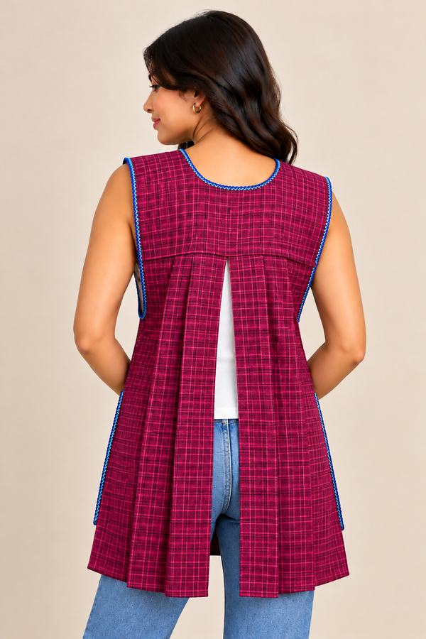 Back view of a burgundy plaid Mexican apron featuring blue decorative stitching, a pleated open-back design, and a sleeveless silhouette.