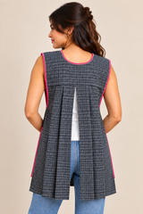 Back view of model wearing a gray plaid Mexican apron with pink trim, an open-back design, and blue jeans.