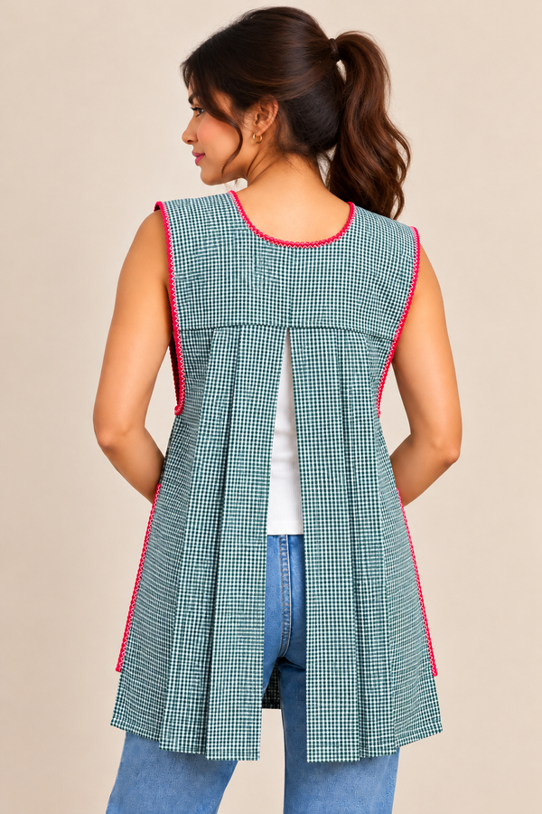 Back view of a handmade Mexican green gingham apron featuring pink trim, sleeveless design, and open-back pleated construction.