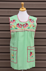 Light green gingham Mexican apron with colorful cross-stitch embroidery and front pockets