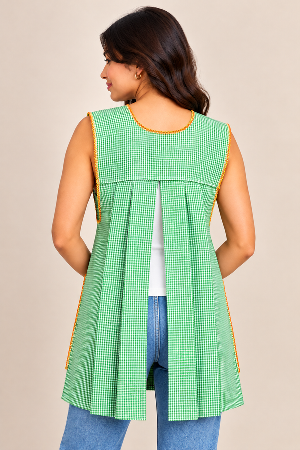 Back view of a handmade Mexican lime green gingham apron featuring an open-back design, pleated fabric panels, and decorative trim.