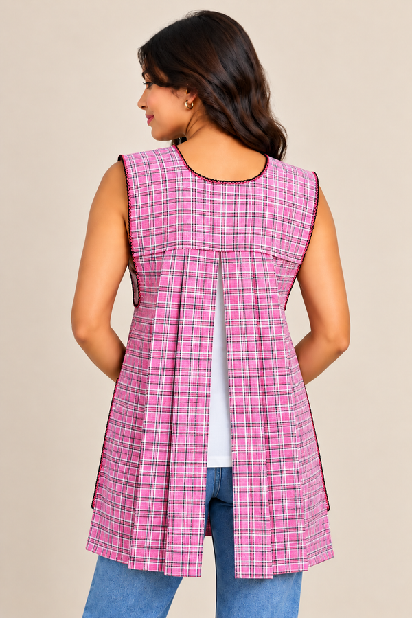 Back view of a handmade Mexican pink plaid apron featuring an open-back design, overlapping fabric panels, and decorative trim.
