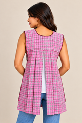 Back view of a handmade Mexican pink plaid apron featuring an open-back design, overlapping fabric panels, and decorative trim.