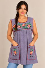 Model wearing a handmade purple checkered Mexican apron with floral embroidery, decorative trim, and two embroidered front pockets.