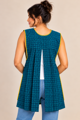 Back view of a teal blue plaid Mexican apron showing the open-back design, gathered fabric panels, and sleeveless cut.