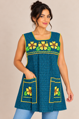 Front view of a handmade Mexican apron with dark teal plaid fabric, yellow floral embroidery, pink trim, and two embroidered pockets.